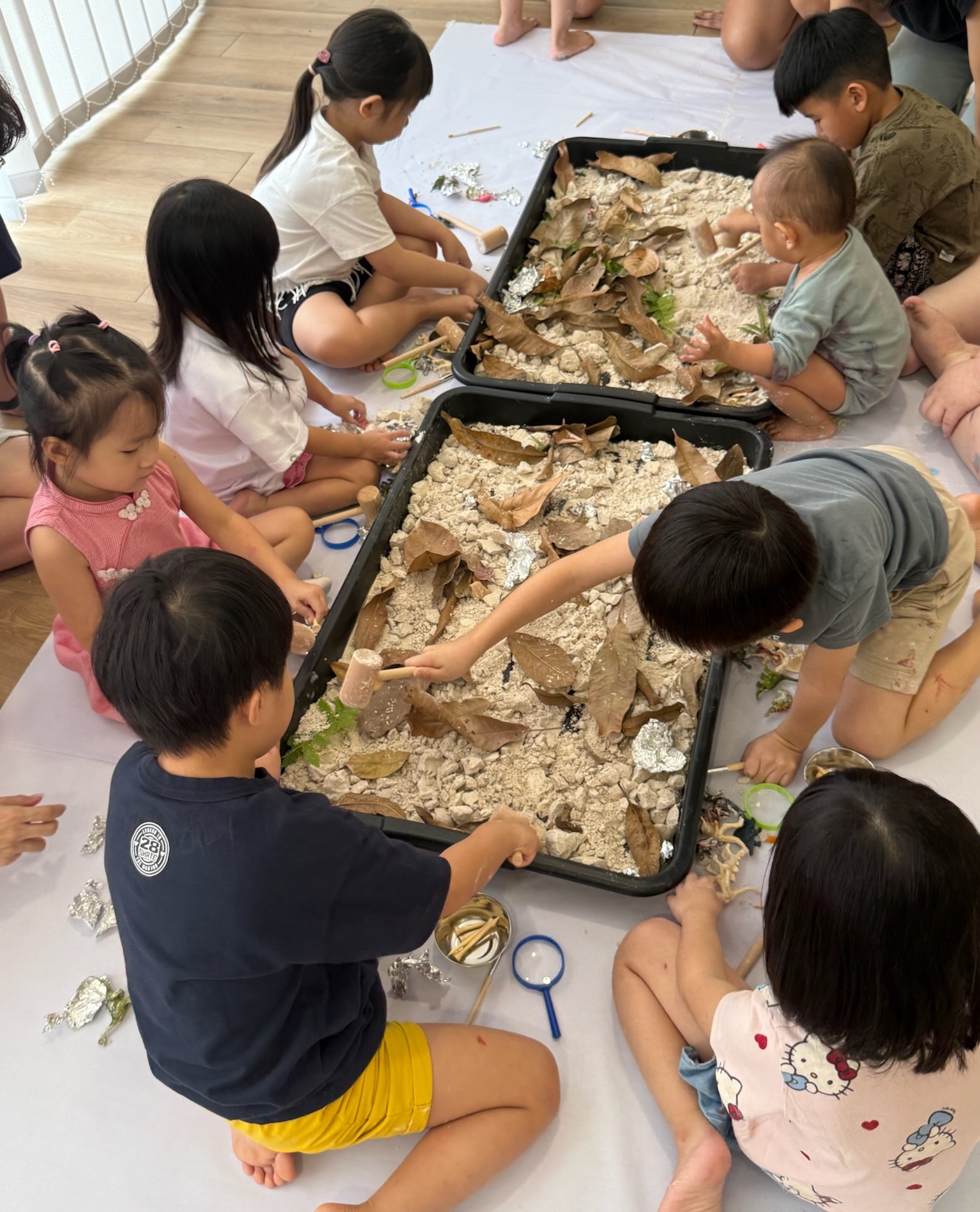 Children digging and exploring together in a messy sensory play tray
