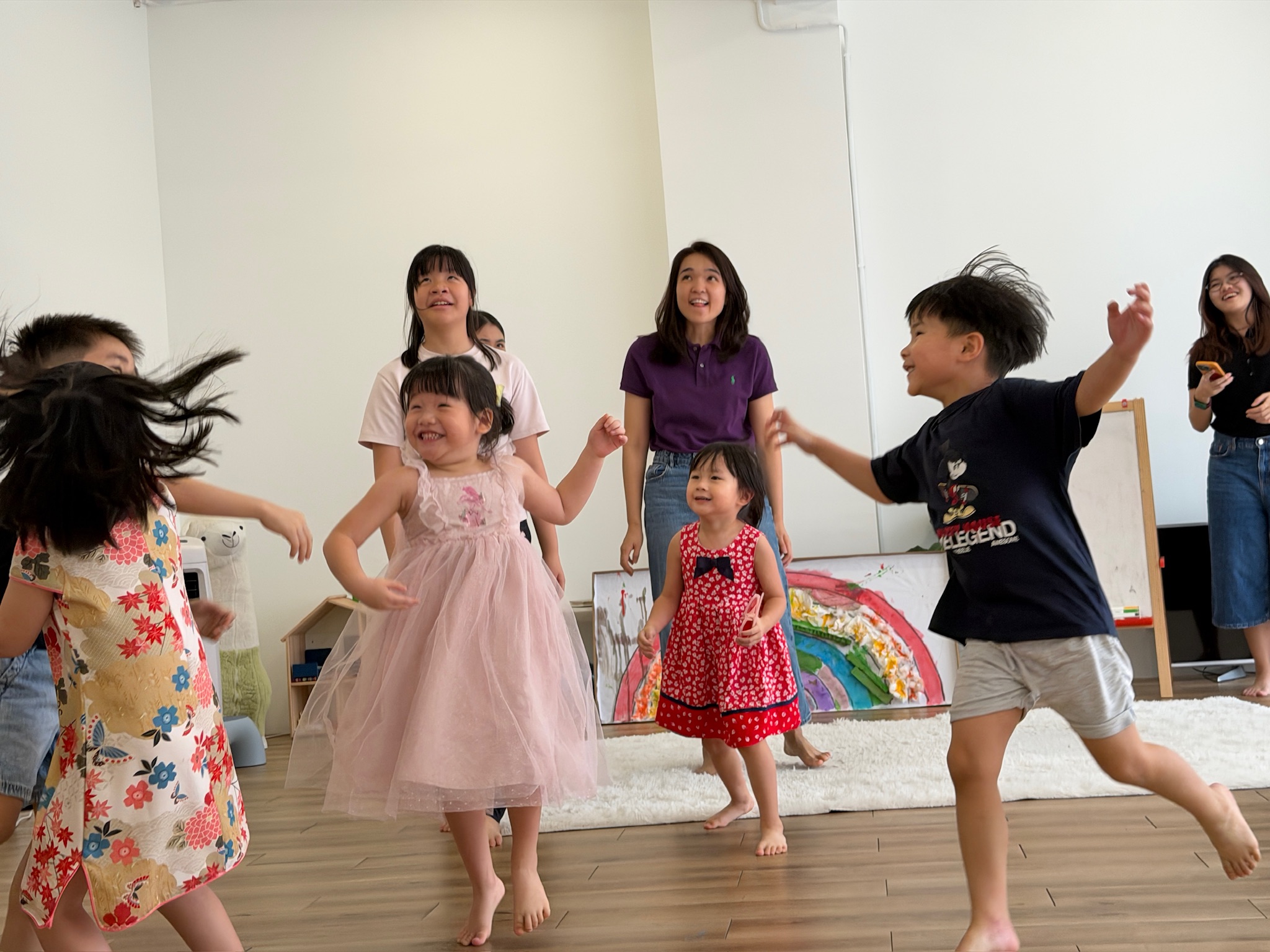 Children dancing and laughing together with their educator during a movement activity