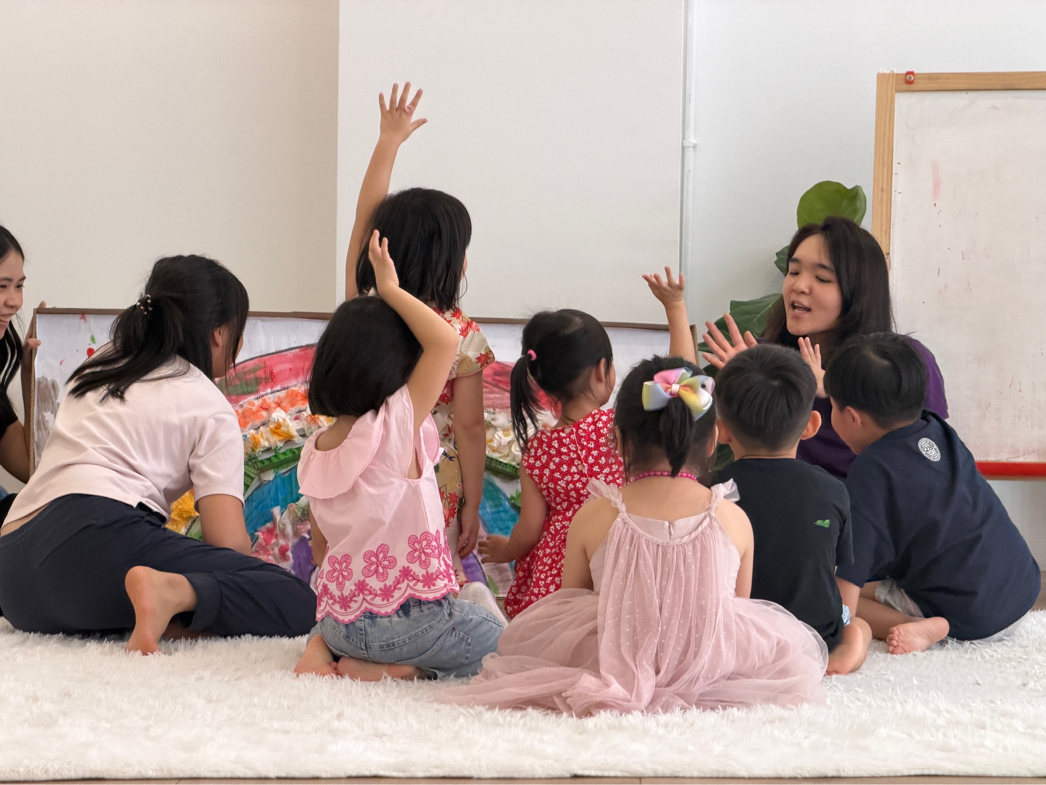 Children raising their hands during a group circle with a facilitator